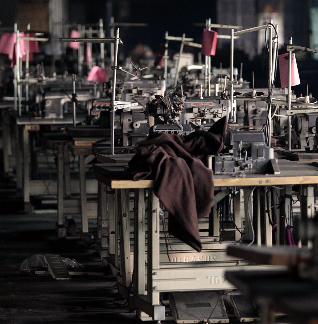 Rows of industrial sewing machines on a clothing factory floor