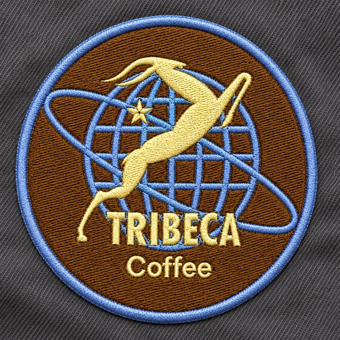 Round embroidered Tribeca Coffee badge with a gold springbok and blue globe